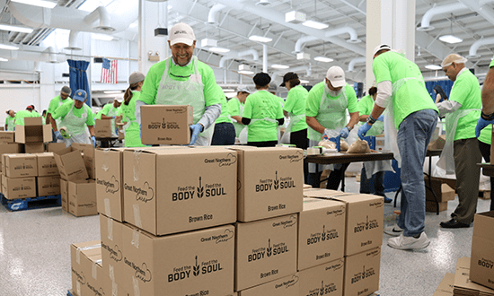 Male stacking a box while volunteering at Oshkosh Corporation's Feed the Body, Feed the Soul event