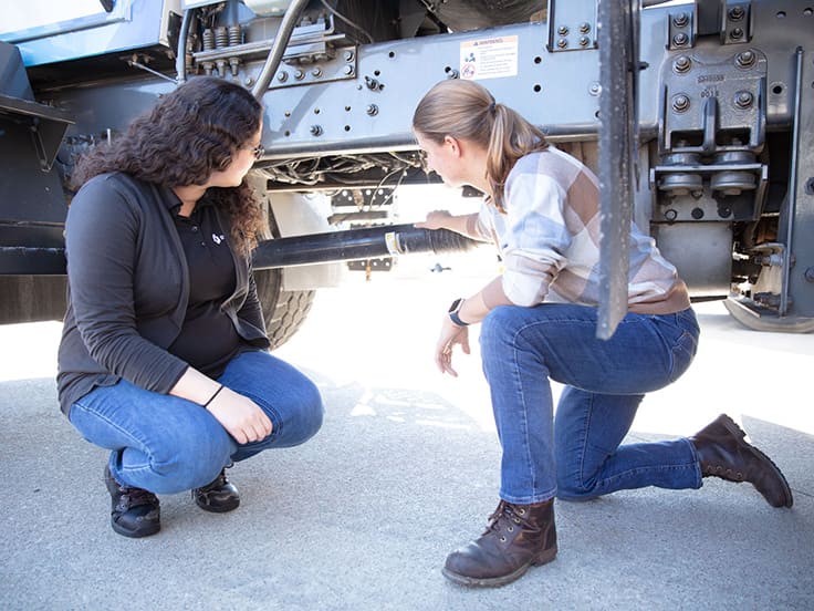 Female engineers looking underneath an Oshkosh S-Series truck