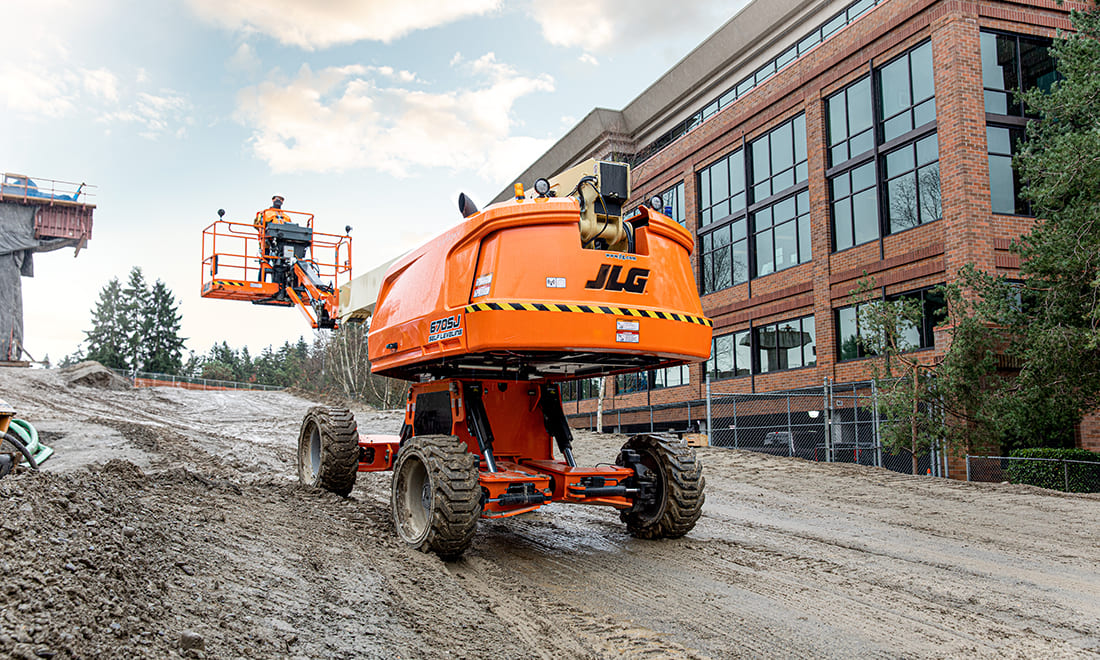 Orange JLG boom lift outside at a construction site