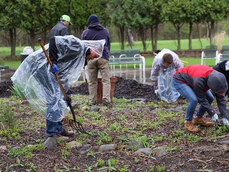 Team members in rain ponchos digging garden