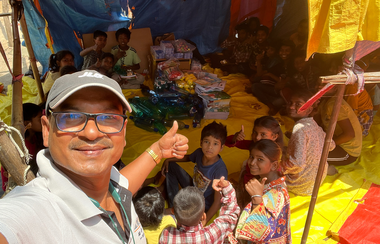 Team member with thumb up with children in India