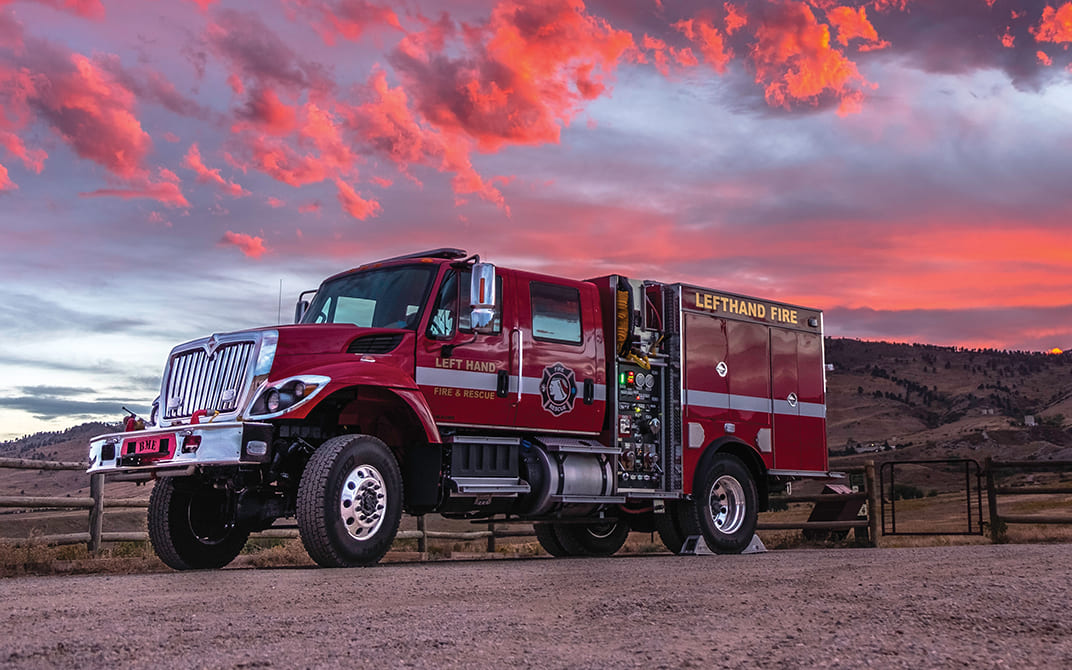 Red fire truck parked outside with a pink and blue sky