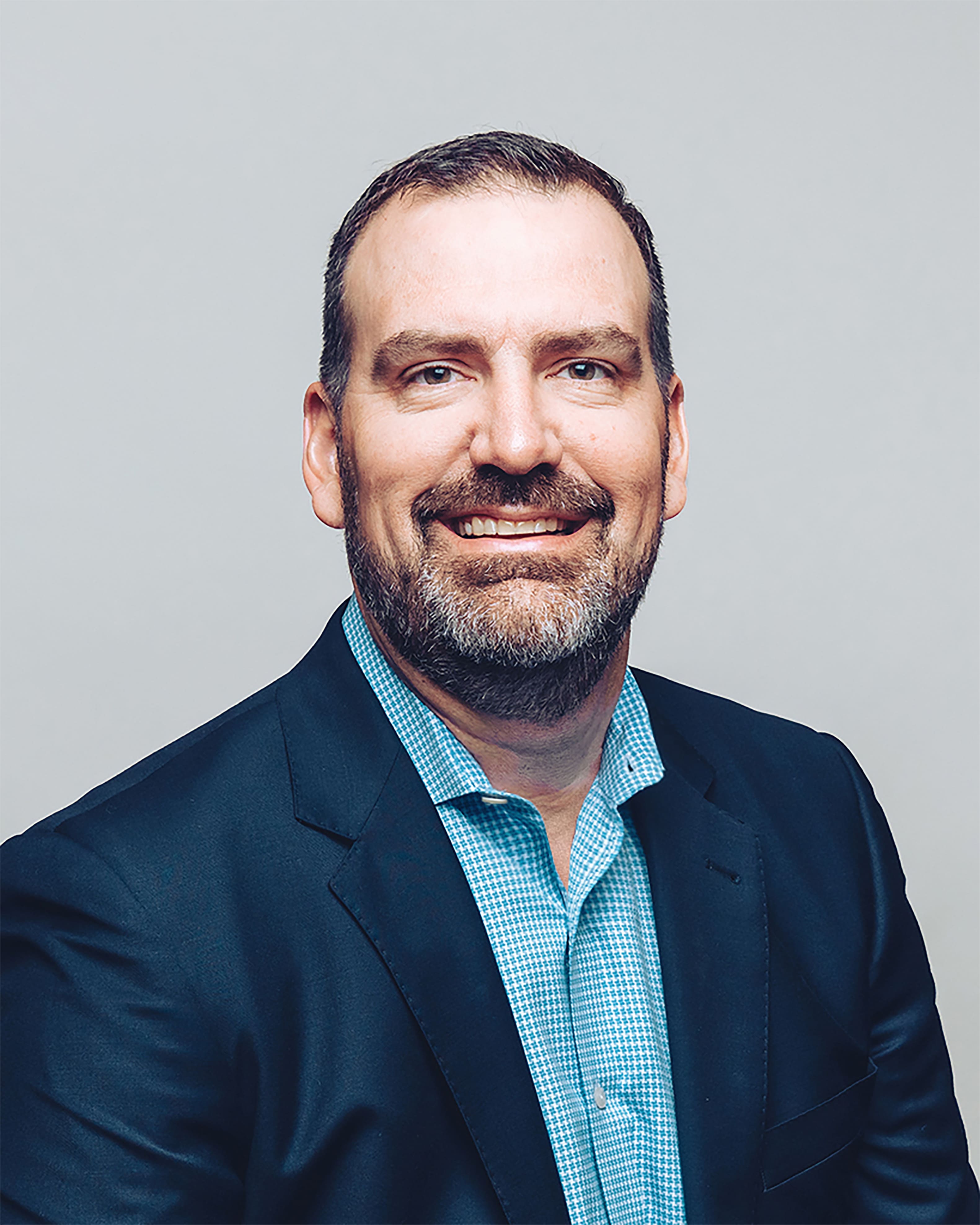 Mike Pack smiling and wearing a dark navy suit jacket